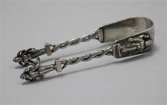 A pair of Indian white metal sugar tongs with figural terminals, 10.8cm.